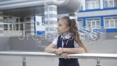 校园里穿着<strong>校服</strong>的漂亮小女孩在一栋小学大楼前的肖像